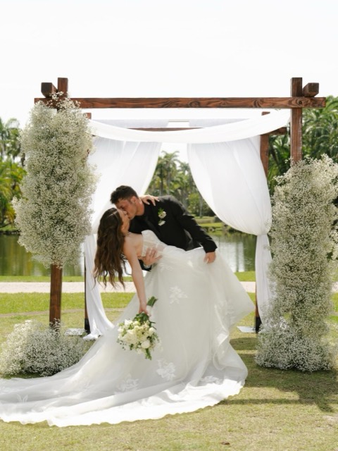 Couple beneath a flower-covered chuppah in Miami sunlight