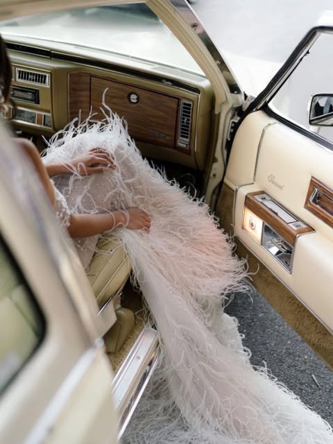 Feathered gown spilling from the door of a vintage car