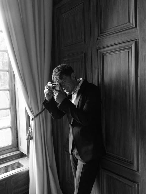 Groom photographing from a townhouse window, black and white